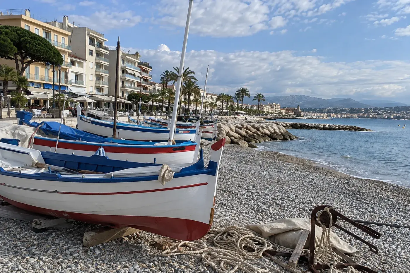 Barques de pêche traditionnelles peintes en blanc, bleu et rouge, tirées sur les galets du Cros-de-Cagnes
